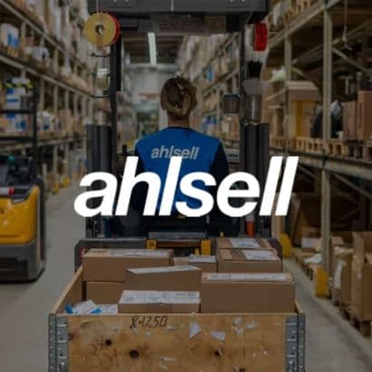 En Ahlsell-lagerarbejder med ryggen til kører gaffeltruck på lageret, med et "ahlsell" logo tydeligt placeret i forgrunden af billedet